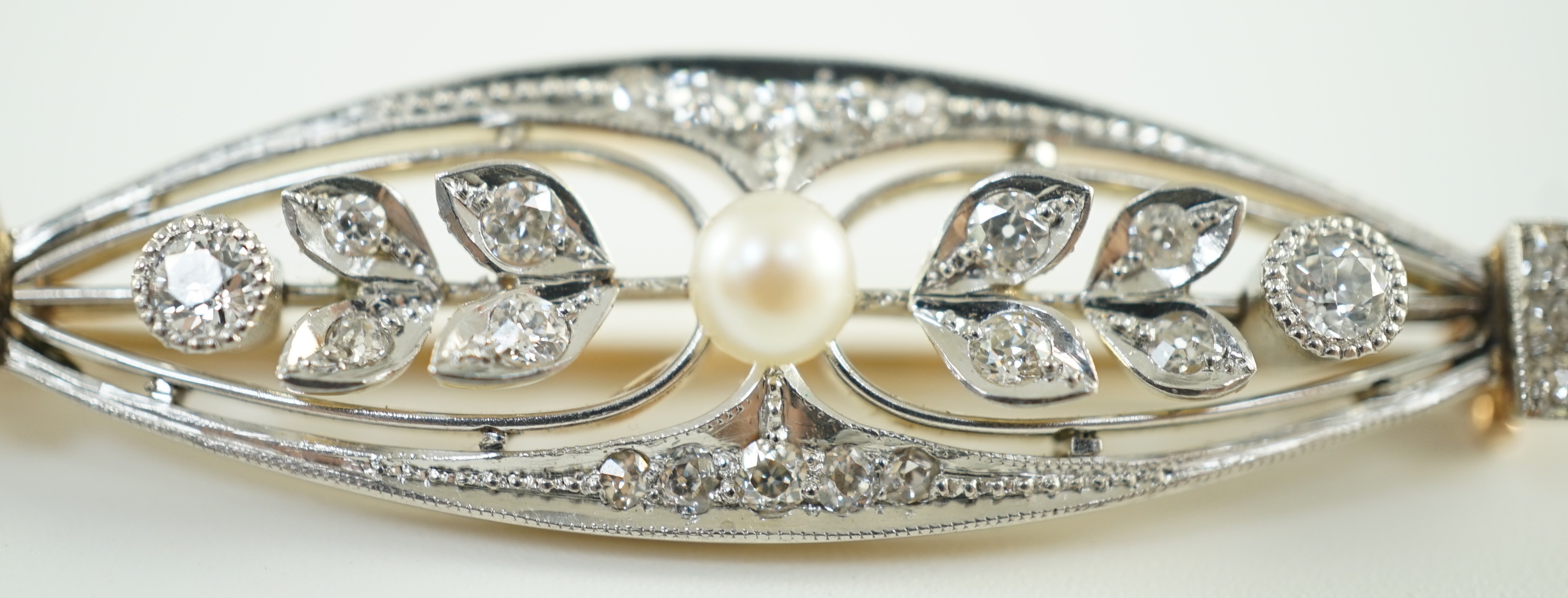 An early to mid 20th century gold and platinum, pearl and round cut millegrain set diamond cluster oval brooch